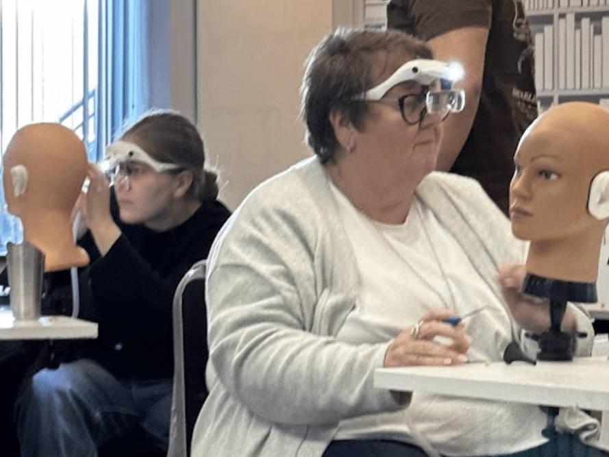 Two trainees practising ear wax removal with head loupes