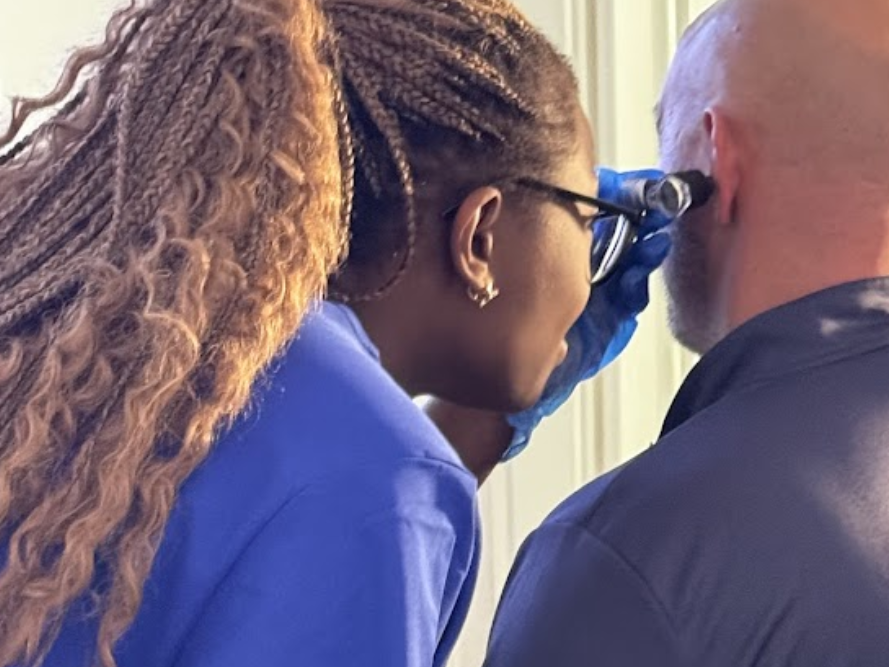 Trainer demonstrating otoscope examination during ear wax removal course
