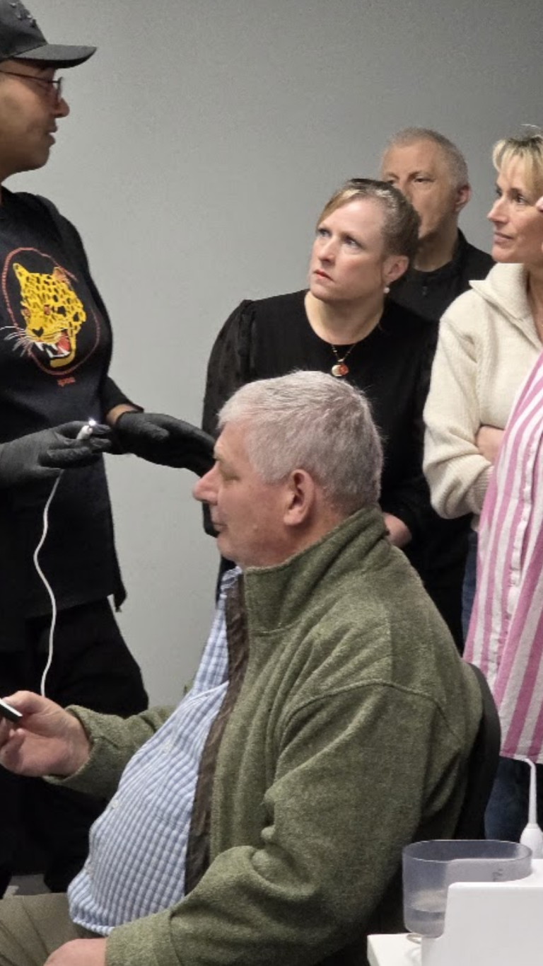 Lead trainer demonstrating live ear examination to group of attendees