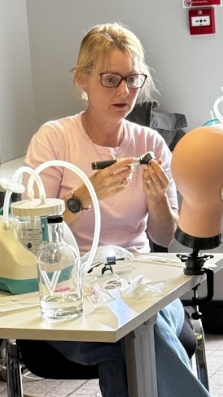 Trainee performing ear examination with head loupe during practical session